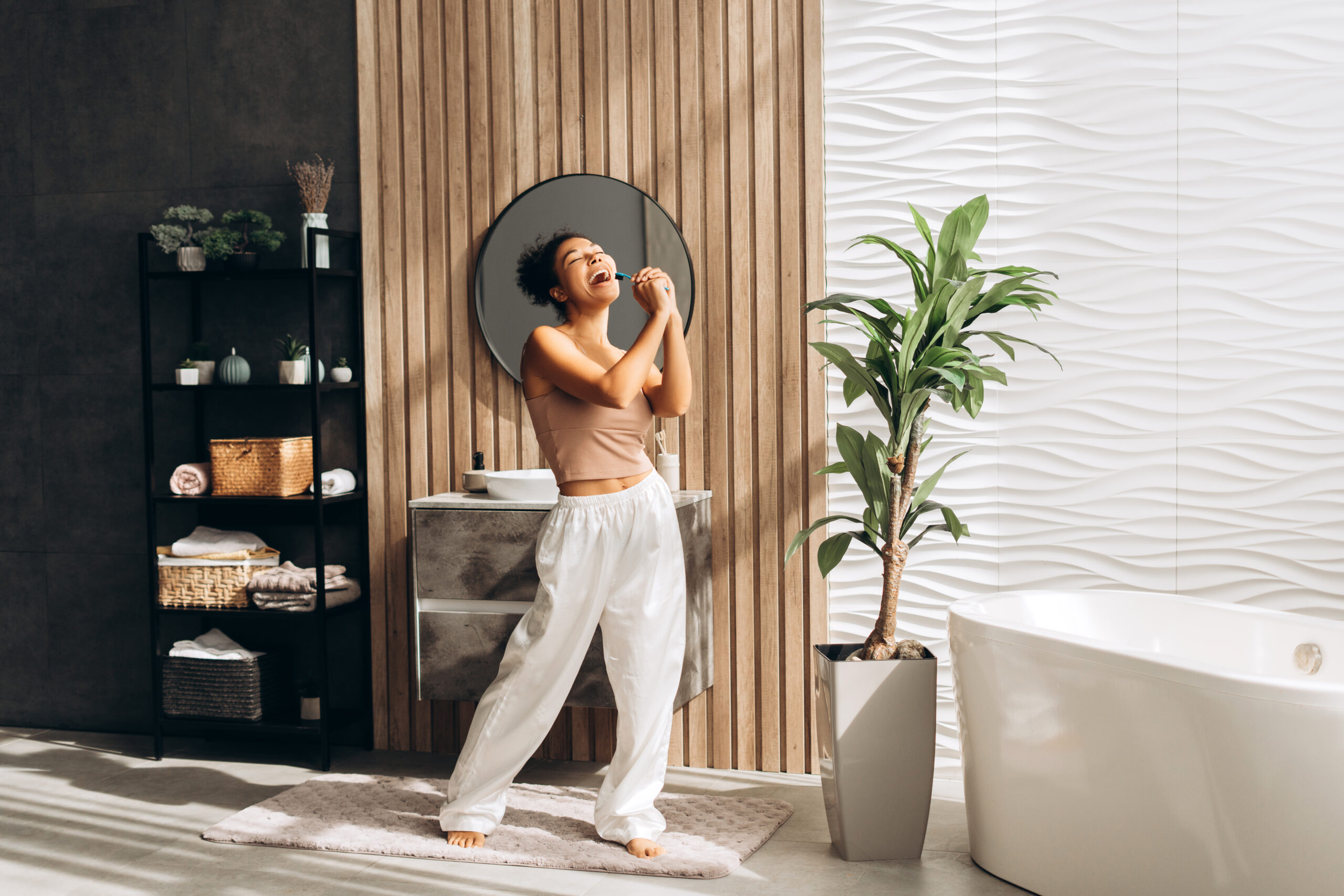 Young woman singing with toothbrush in modern bathroom