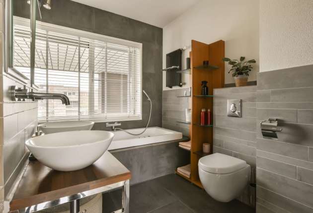 a bathroom with a sink, toilet and window in the back wall is made of dark grey tiles on the floor