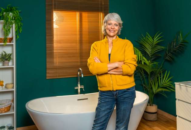 Mature woman standing with arms crossed on a modern bathroom Casual caucasian mature woman standing with arms crossed on a modern bathroom